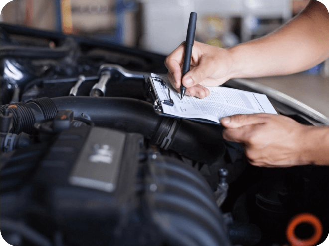 A person writing on paper in front of an engine.